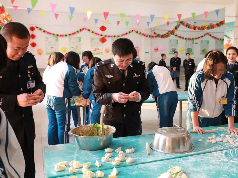 （用）省司法廳戒毒管理局局長段劍平（中）同干警、戒毒學員一起包餃子。