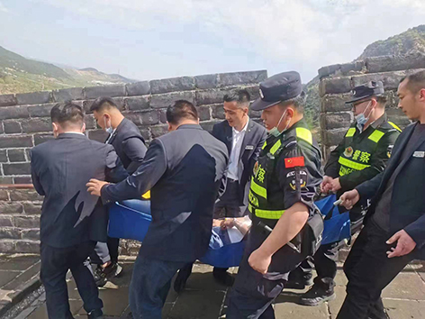 民警與景區(qū)工作人員將患病游客抬下長(zhǎng)城。