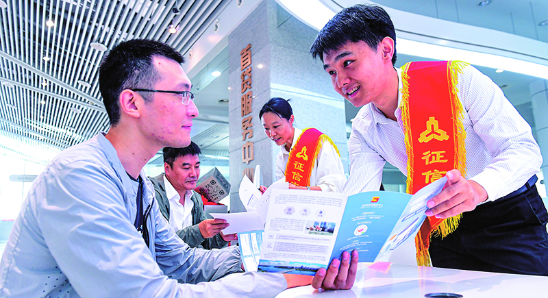 征信志愿服務大隊志愿者在首貸服務中心為前來咨詢征信業(yè)務的群眾進行業(yè)務講解